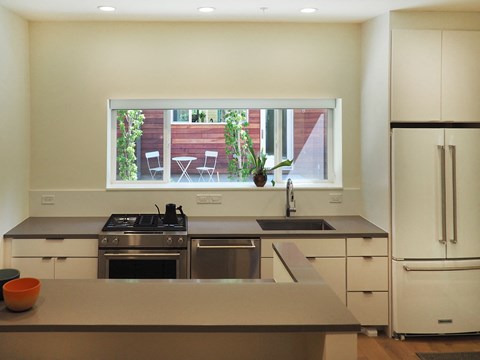 A kitchen with a stove, sink, and refrigerator.