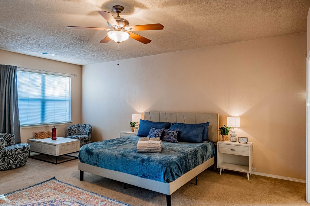 the master bedroom has a king sized bed and a ceiling fan