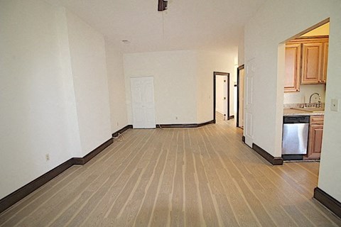 an empty living room and kitchen with a wood floor