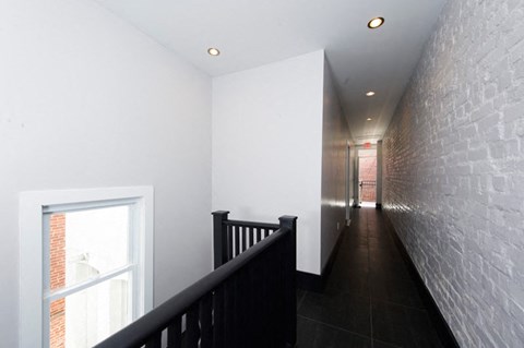 a hallway with stairs and a brick wall and a window