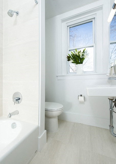 a white bathroom with a white toilet and a window