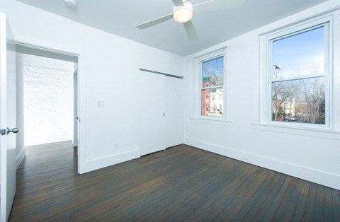 an empty living room with white walls and a ceiling fan