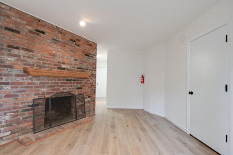 a living room with a brick fireplace and wooden floors