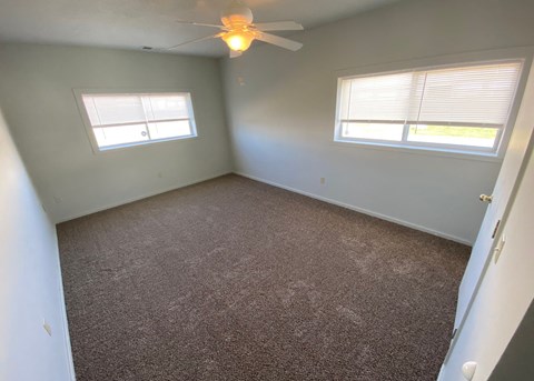 a bedroom with a carpeted floor and a ceiling fan