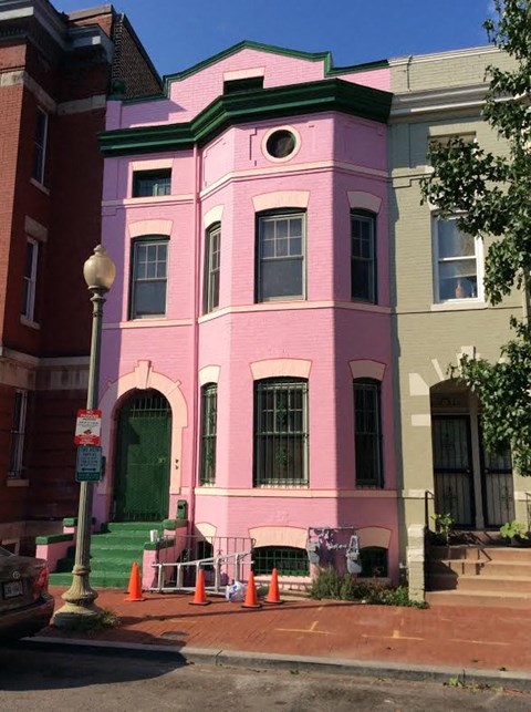 A pink building with a green door and windows.