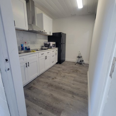 a kitchen with white cabinets and black appliances and a wood floor