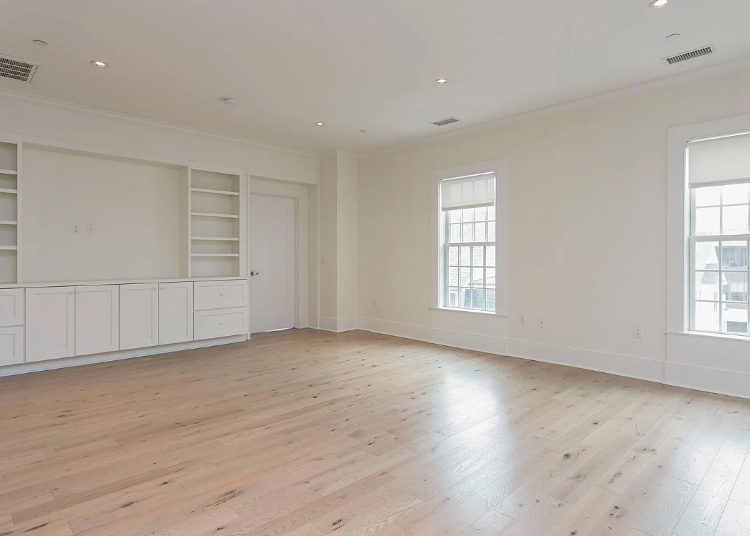 A large empty room with wooden floors and white walls.
