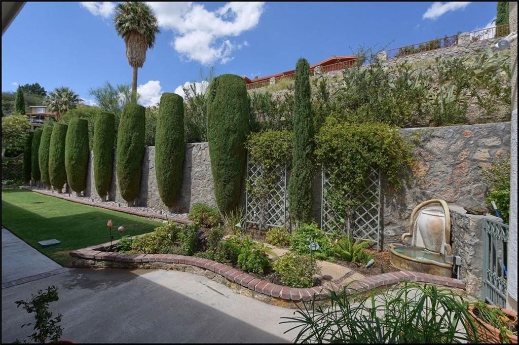 the backyard has a garden and a stone wall with trees and a fountain