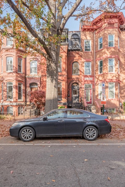 A black car is parked in front of a red brick building.