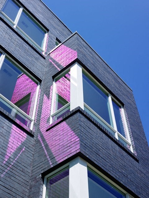 a pink brick building with windows and a blue sky
