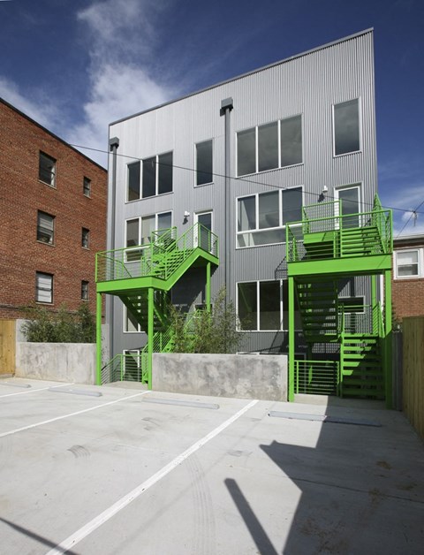 the exterior of an apartment building with green stairs