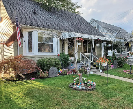 A house with a flag on the left side and a garden in front.