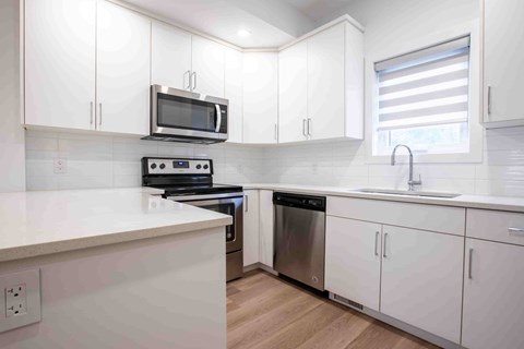 A kitchen with white cabinets and a black microwave.