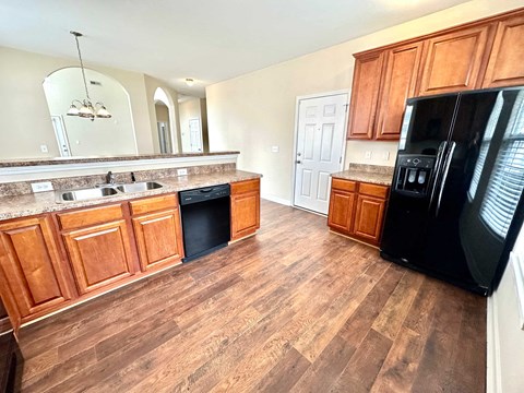 A kitchen with wooden cabinets and a black refrigerator.