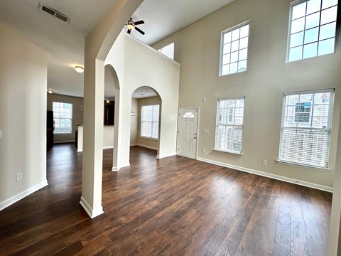 A spacious room with wooden floors and arched columns.