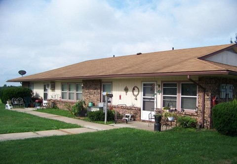 a house with a brown roof and a patio with chairs