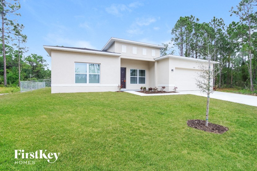 a white house with a lawn and a tree
