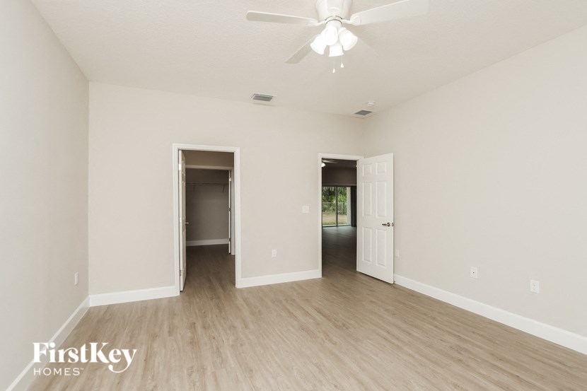 an empty living room with white walls and a ceiling fan