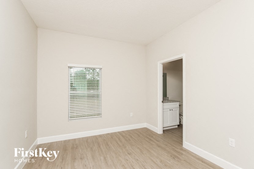 a bedroom with white walls and wood flooring and a doorway to a bathroom