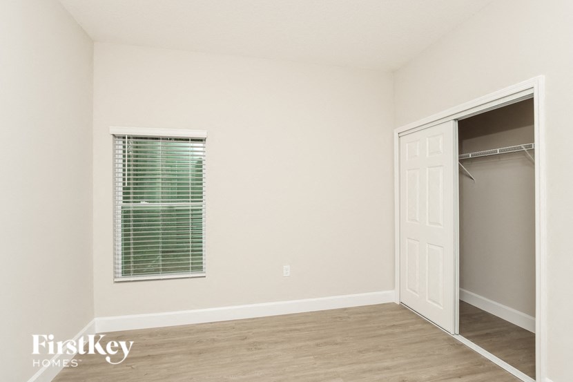a bedroom with a closet and a window and a door to a closet