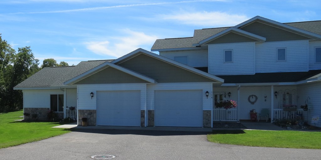 a white house with white garage doors and a gray roof