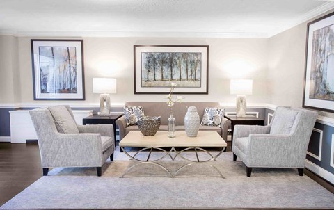 A living room with a grey sofa, two chairs, a coffee table, and two wall lamps.