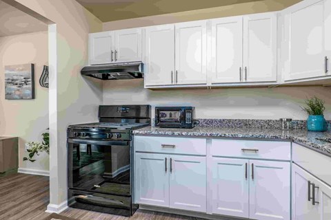 A kitchen with white cabinets and a black stove top oven.