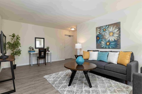 A living room with a grey couch, a wooden coffee table, and a painting on the wall.