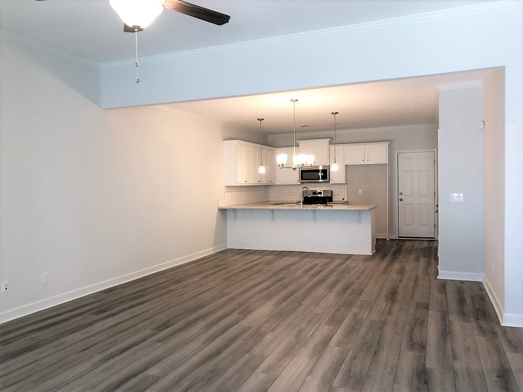 A room with a ceiling fan and a kitchenette.
