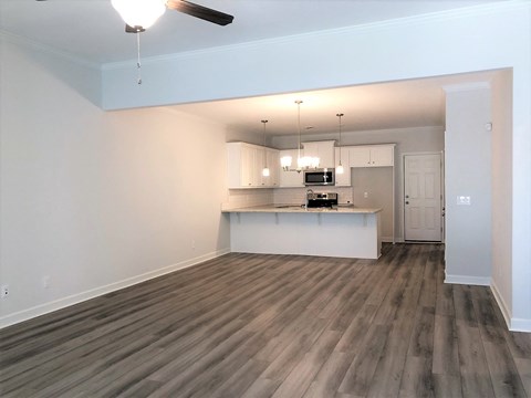 A room with a ceiling fan and a kitchenette.