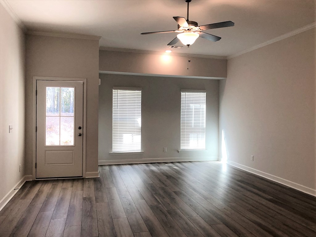 A room with a ceiling fan and wooden flooring.