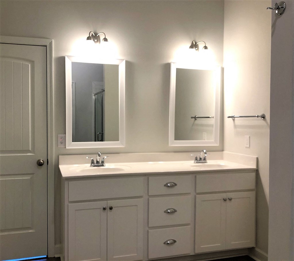 A white bathroom vanity with two sinks and two mirrors.