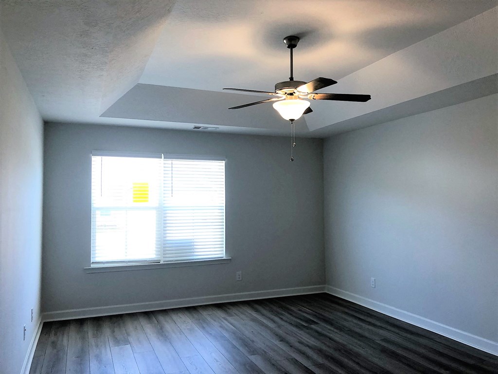 A room with a ceiling fan and a window with blinds.