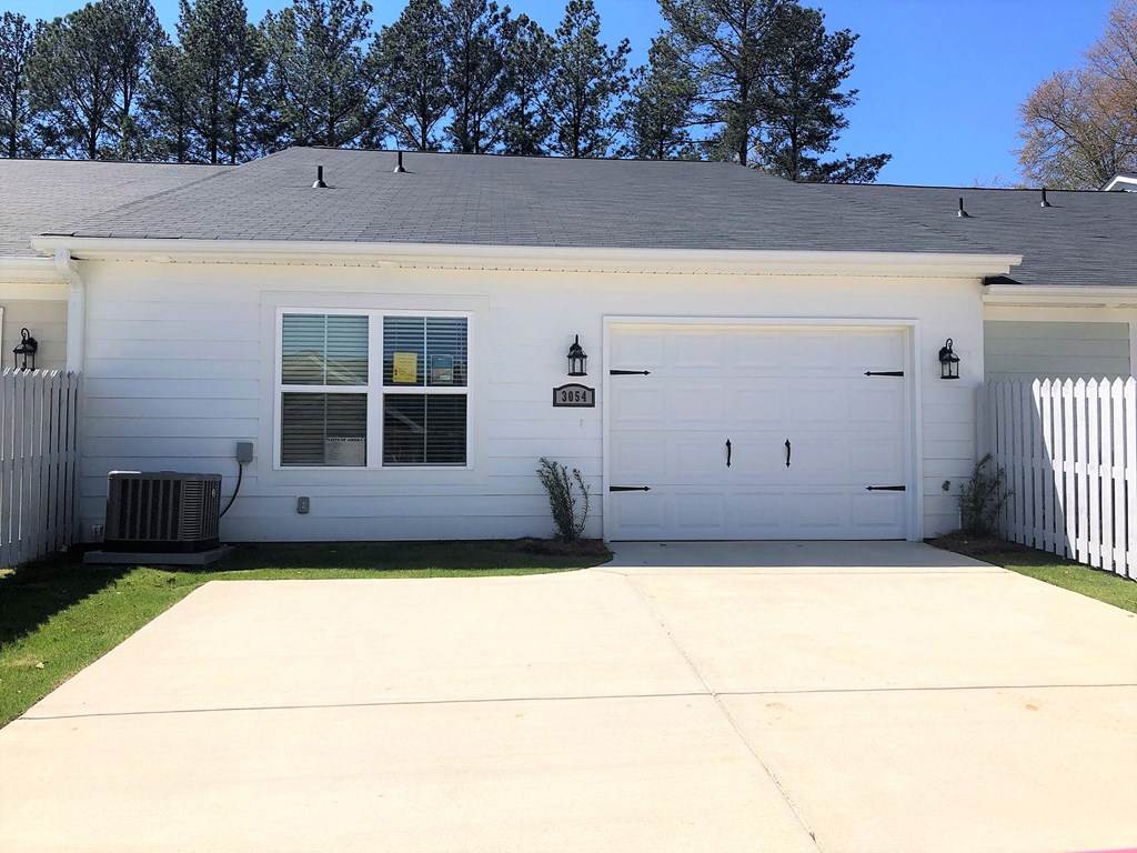 A white house with a grey roof and a white fence.
