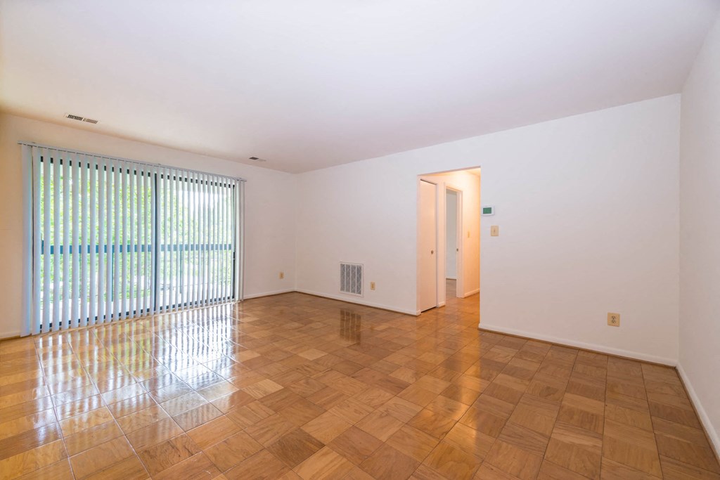 A room with wooden flooring and a window with blinds.