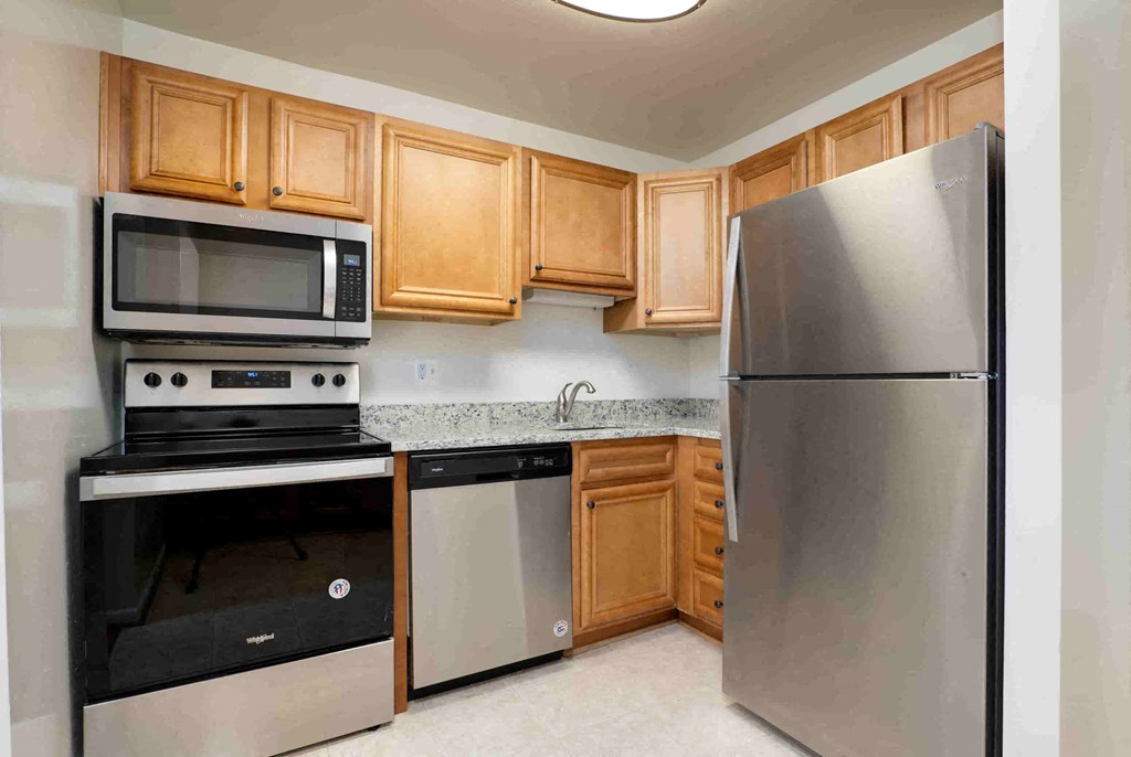 A kitchen with a stainless steel refrigerator, microwave, oven, and dishwasher.