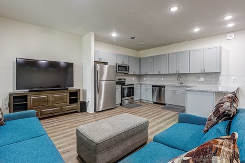 a living room with a blue couch and a kitchen with stainless steel appliances