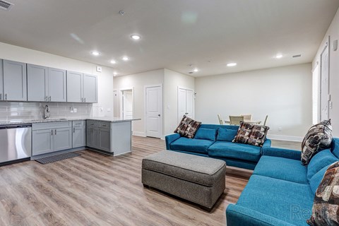 a living room with a blue couch and a kitchen with a sink