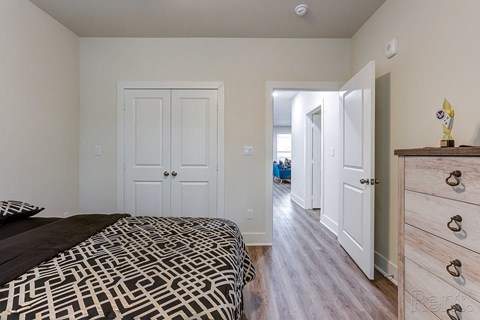 a bedroom with a bed and a dresser and a hallway with a closet