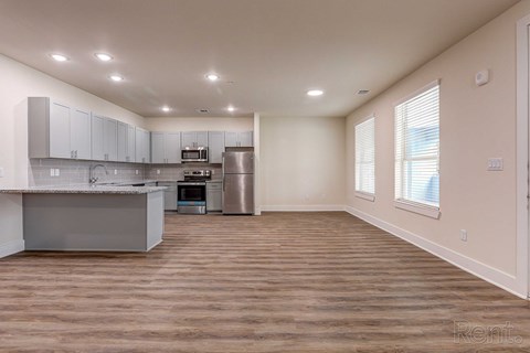 an empty kitchen with white cabinets and a stainless steel refrigerator