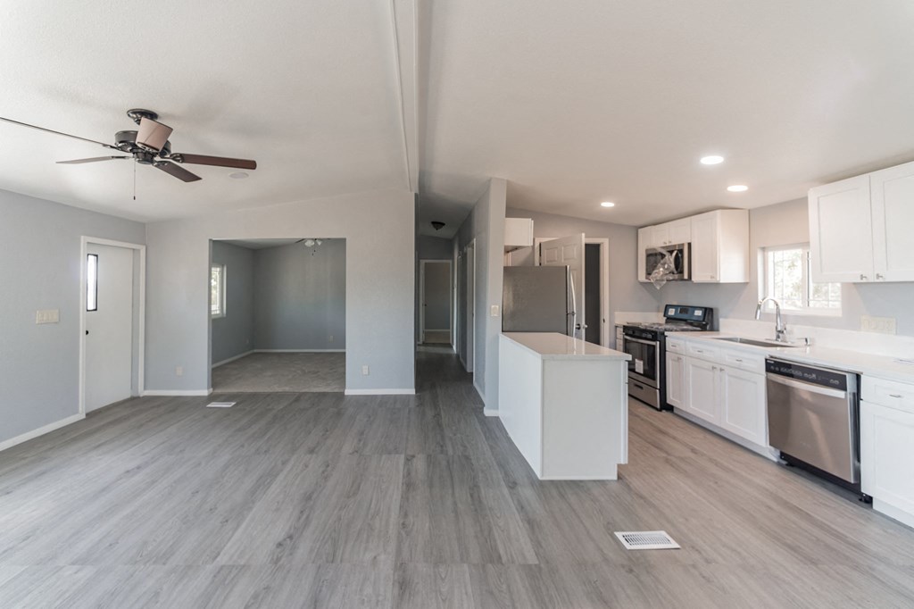 an empty kitchen and living room with a ceiling fan