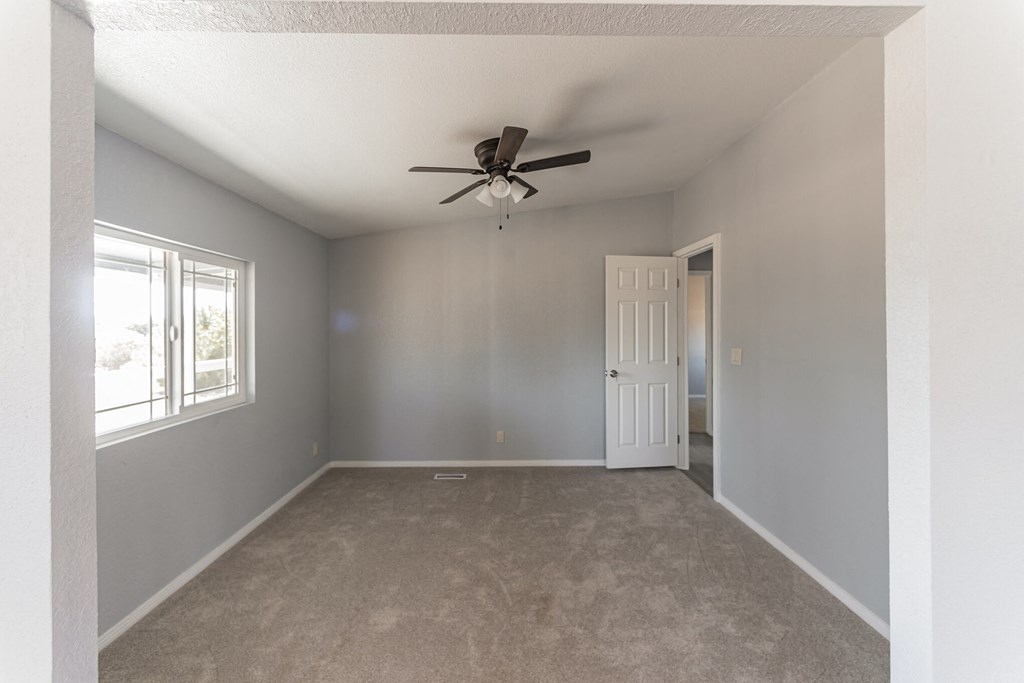 an empty living room with a ceiling fan