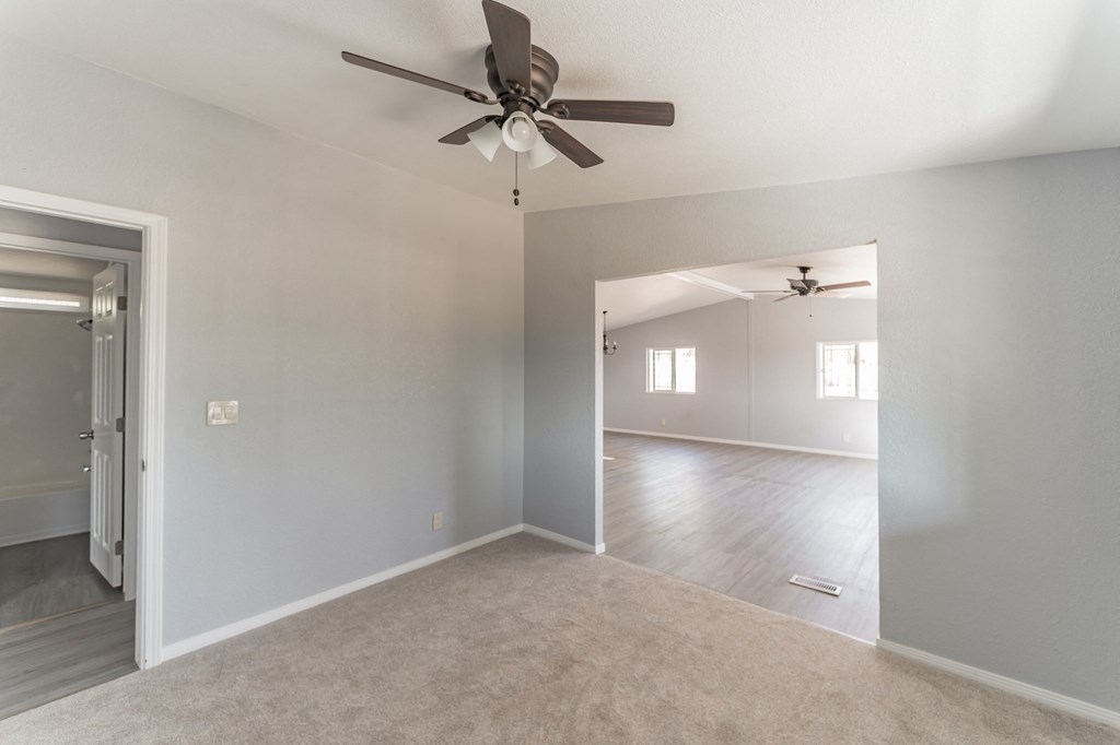 the living room and dining room of an empty house with a ceiling fan