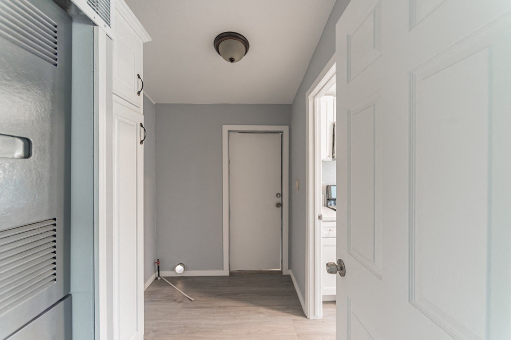 a hallway with white doors and a white door open to a closet