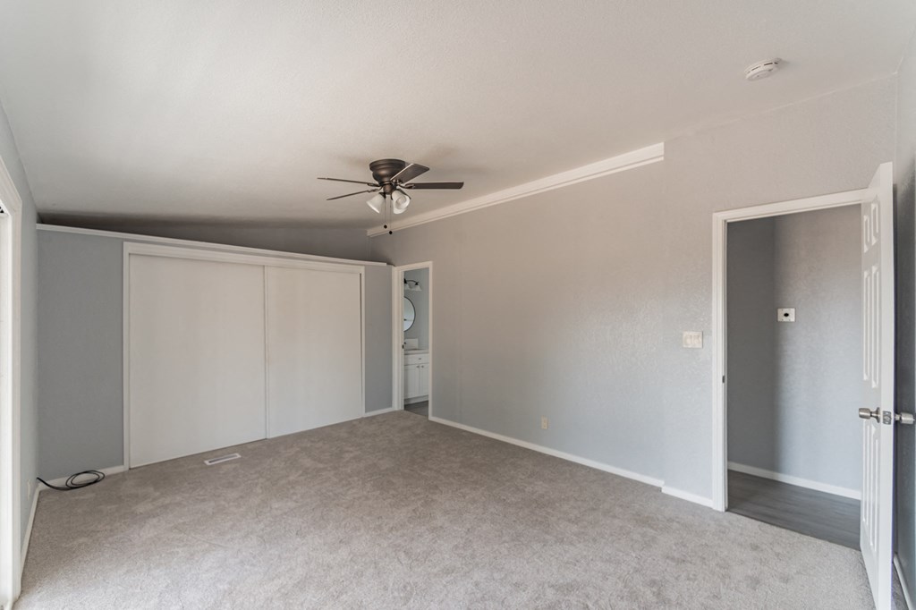 an empty living room with a ceiling fan and a closet