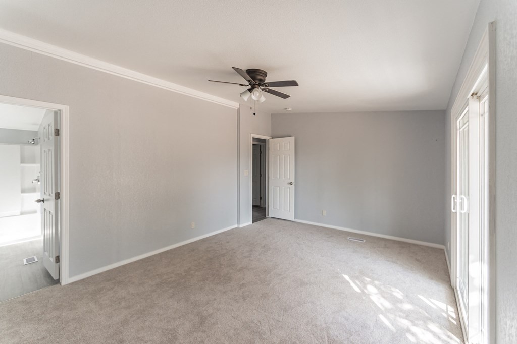 an empty living room with a ceiling fan