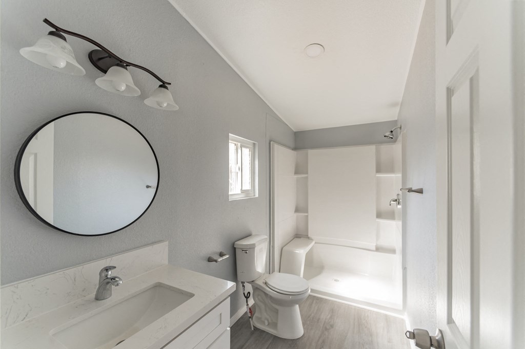 a white bathroom with a toilet and a sink and a mirror