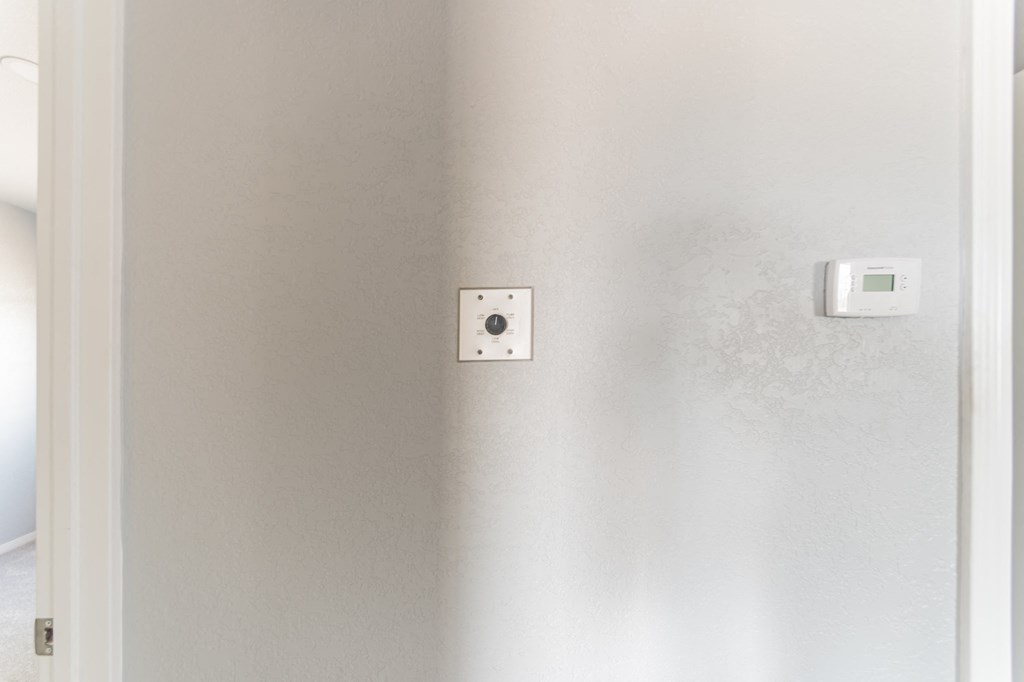 a white thermostat on a wall next to a white door