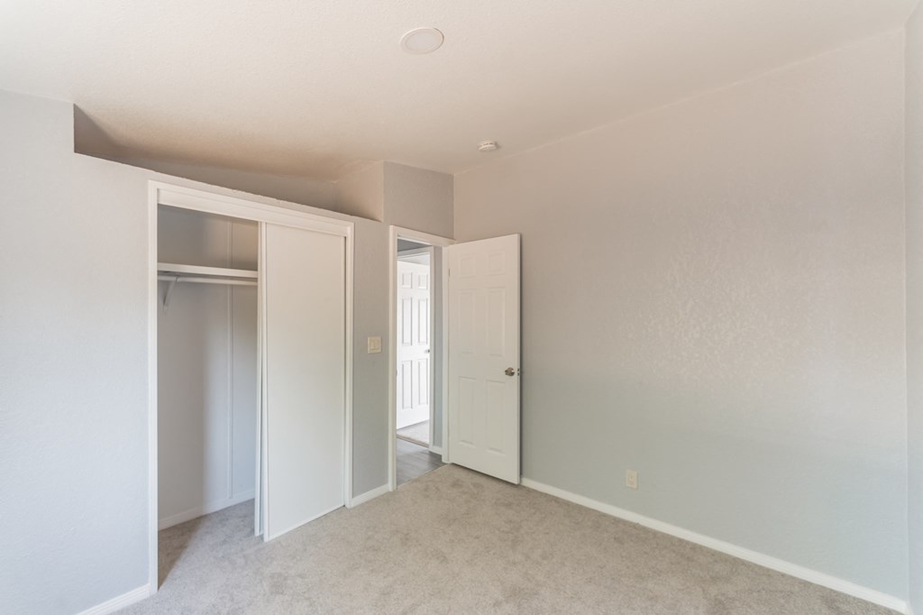 an empty bedroom with a closet and a door to a hallway