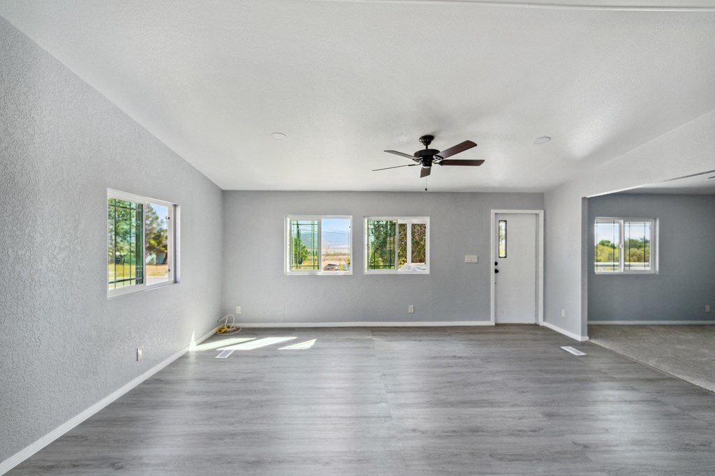 an empty living room with a ceiling fan and windows